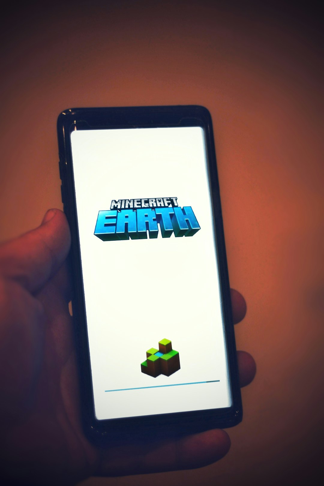 a hand holding a cell phone with a game on the screen downloading video mp3 android