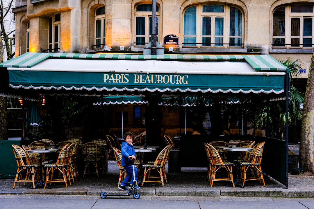 a person riding a scooter in front of a restaurant paris travel charging devices coffee laptop