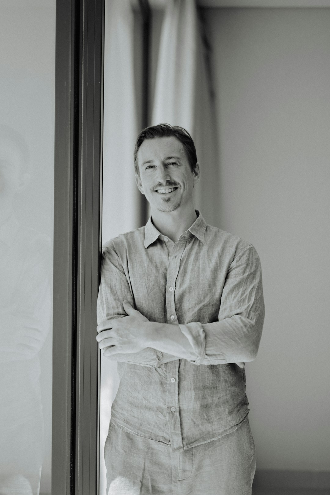 man with arms crossed smiling by window lance crosby tech entrepreneur cloud computing