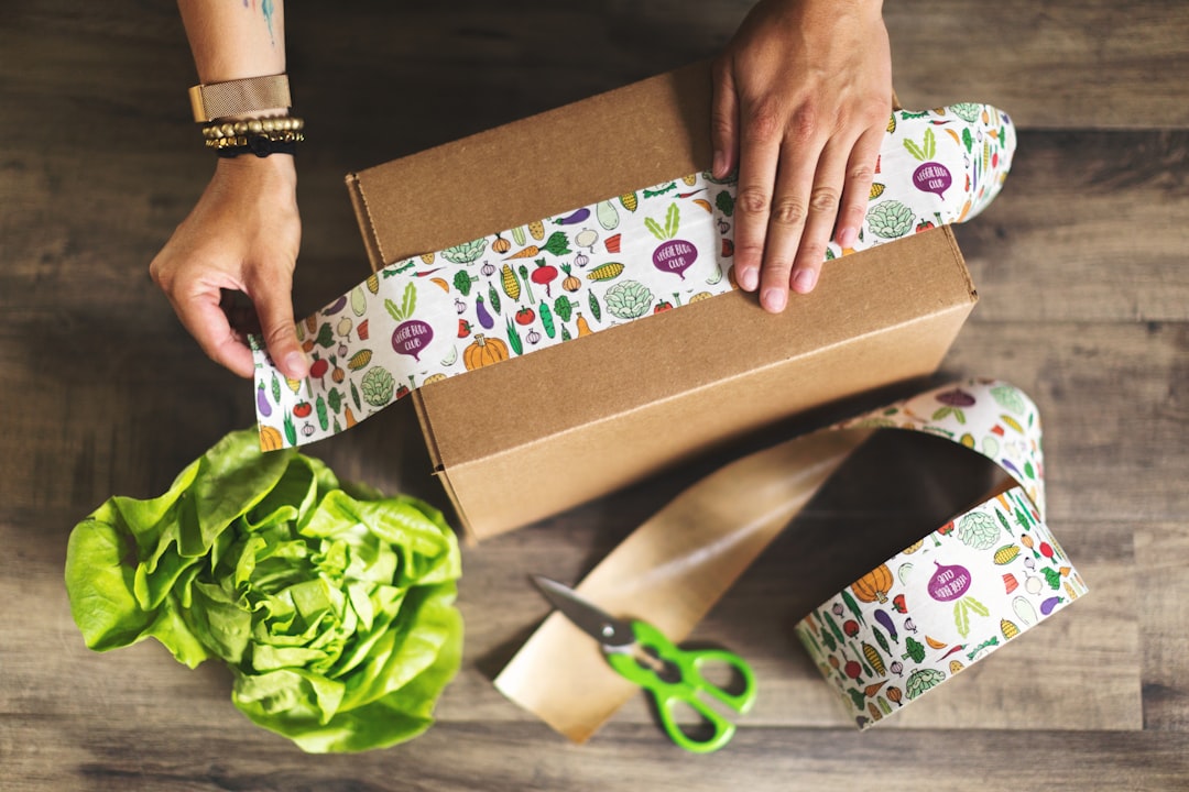 person holding brown and white gift box amazon uk delivery boxes online shopping