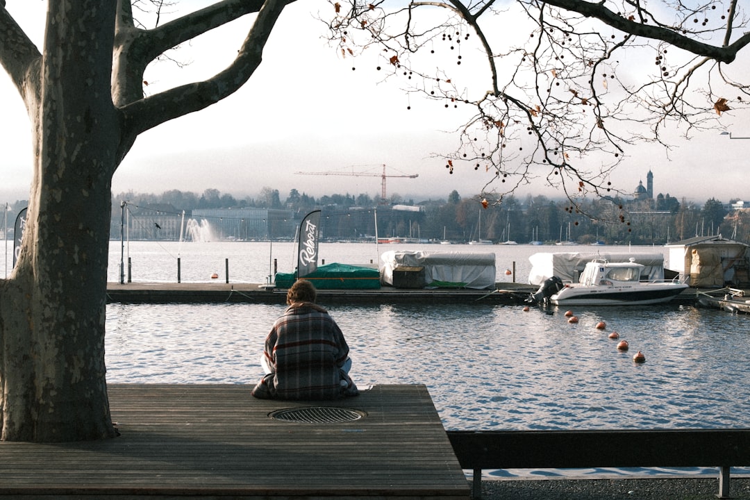 person sitting by the water with boats docked calm person mindfulness peaceful moment