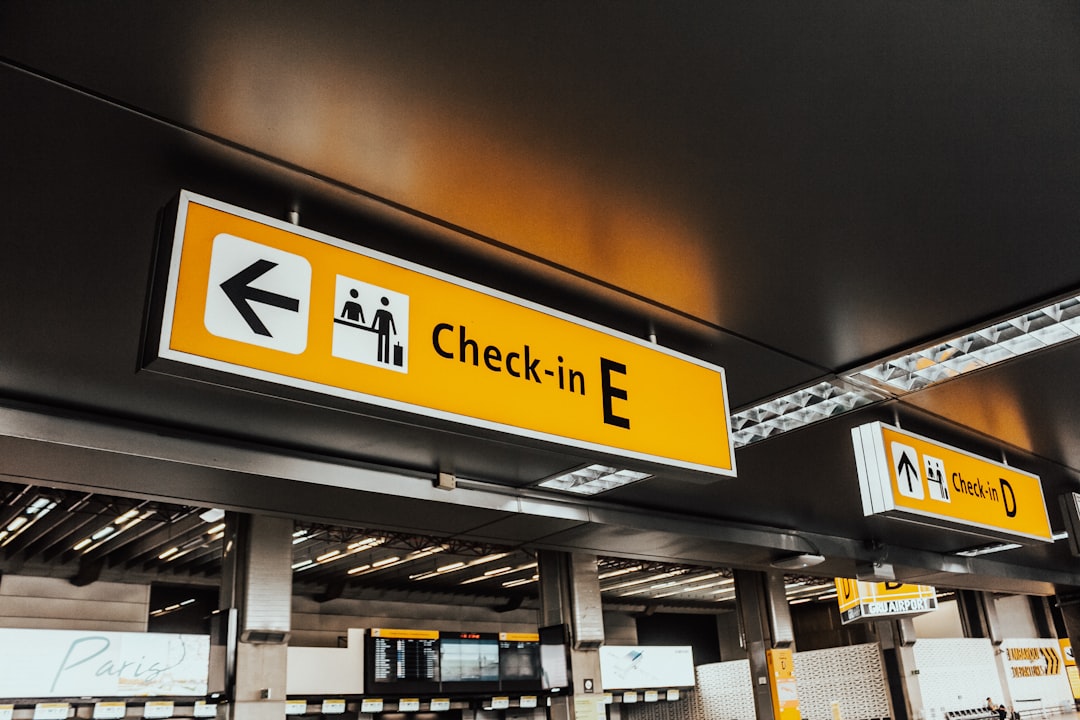 How to Add TSA PreCheck to Your American Airlines Profile 2 a yellow and white check in sign hanging from a ceiling boarding pass airport checkin tsa precheck indicator
