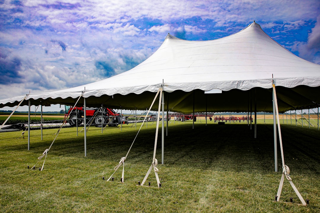 a large white tent sitting on top of a lush green field community event small business tent neighborhood fair