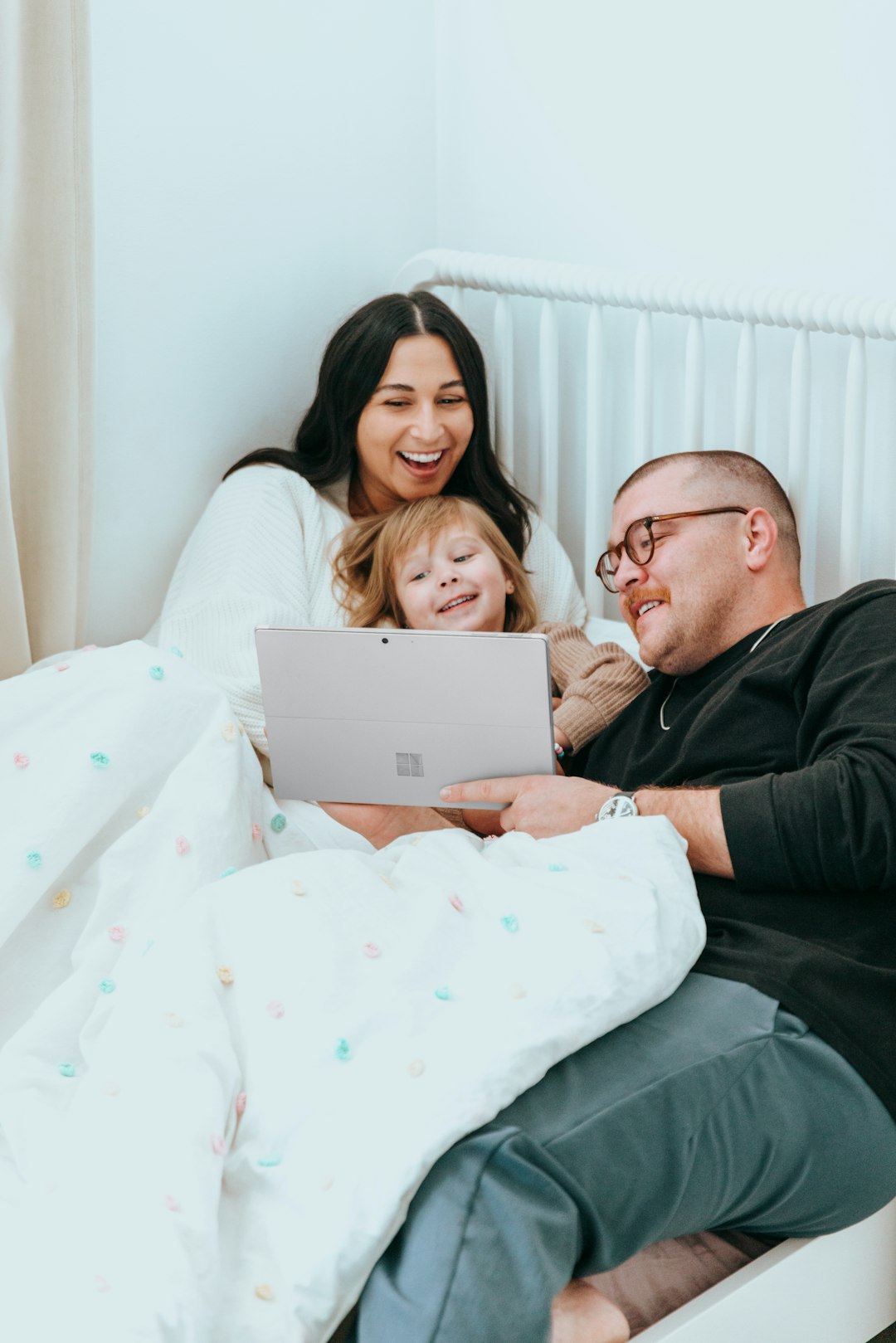 a man and a woman sitting on a bed with a laptop happy family using computer kids internet safety technology fun