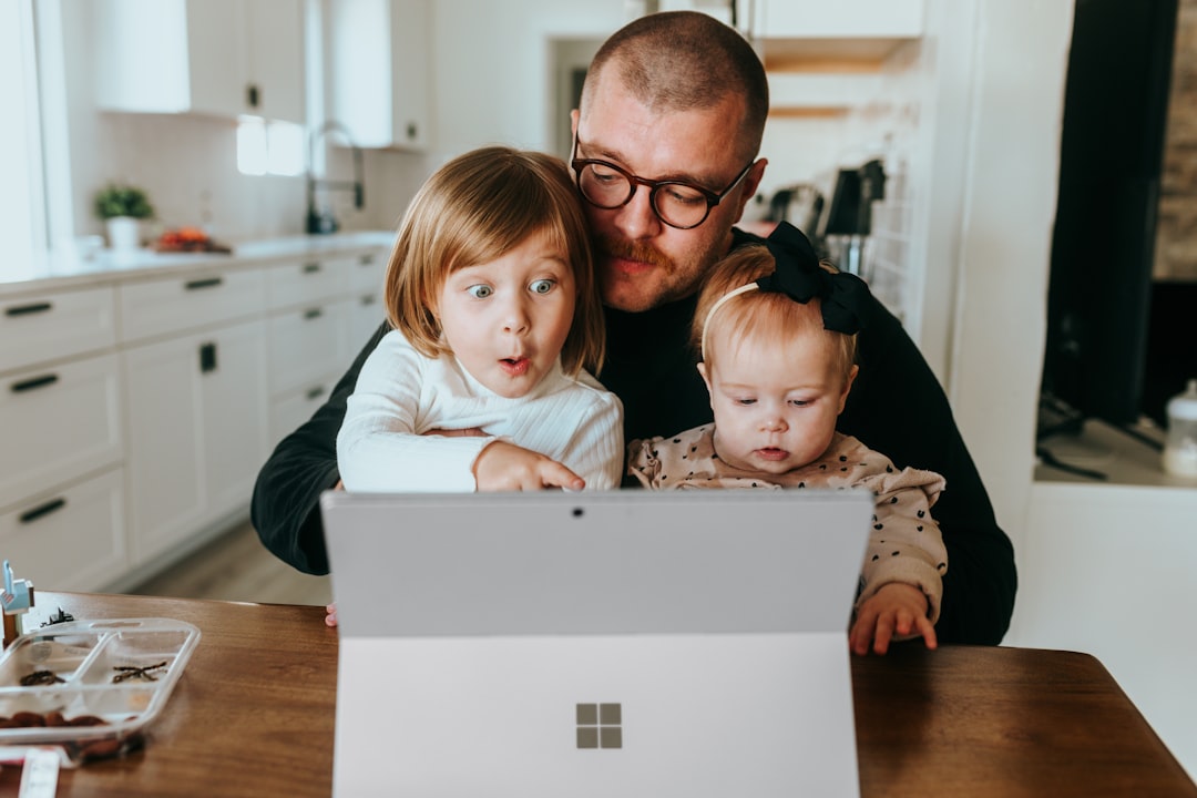 How to Protect Your Kids Online in the U.S. with a VPN in 2025 2 a man and two children looking at a laptop happy family using computer kids internet safety technology fun