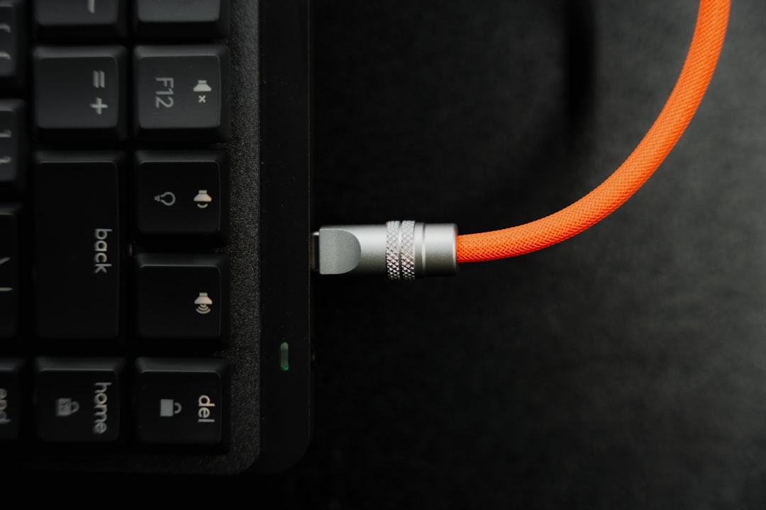 a close up of a computer keyboard with an orange cord ethernet cable gaming setup stable connection