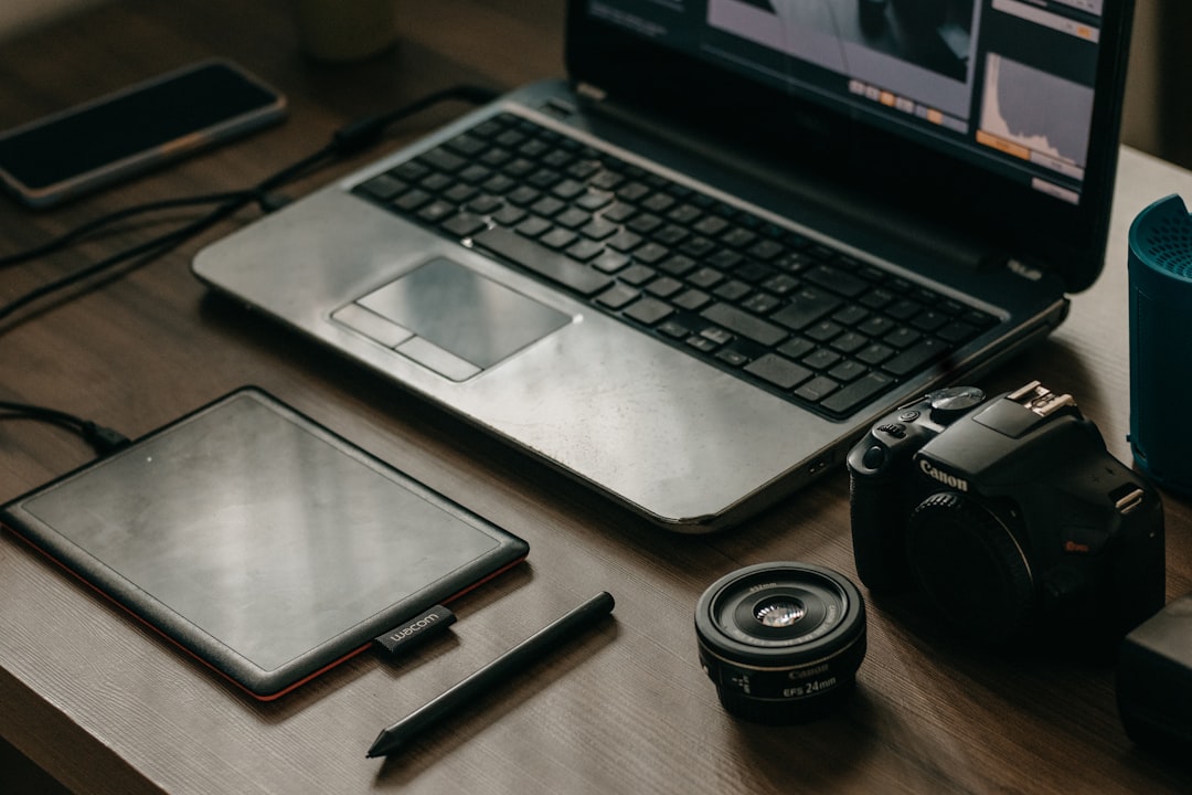 a laptop computer sitting on top of a wooden desk photographer at computer editing photos online tools