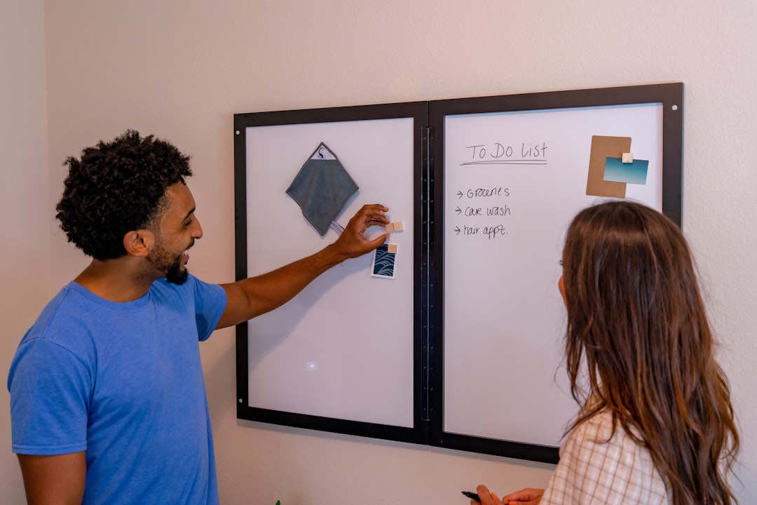 a man and a woman standing in front of a whiteboard miro board virtual whiteboard team collaboration