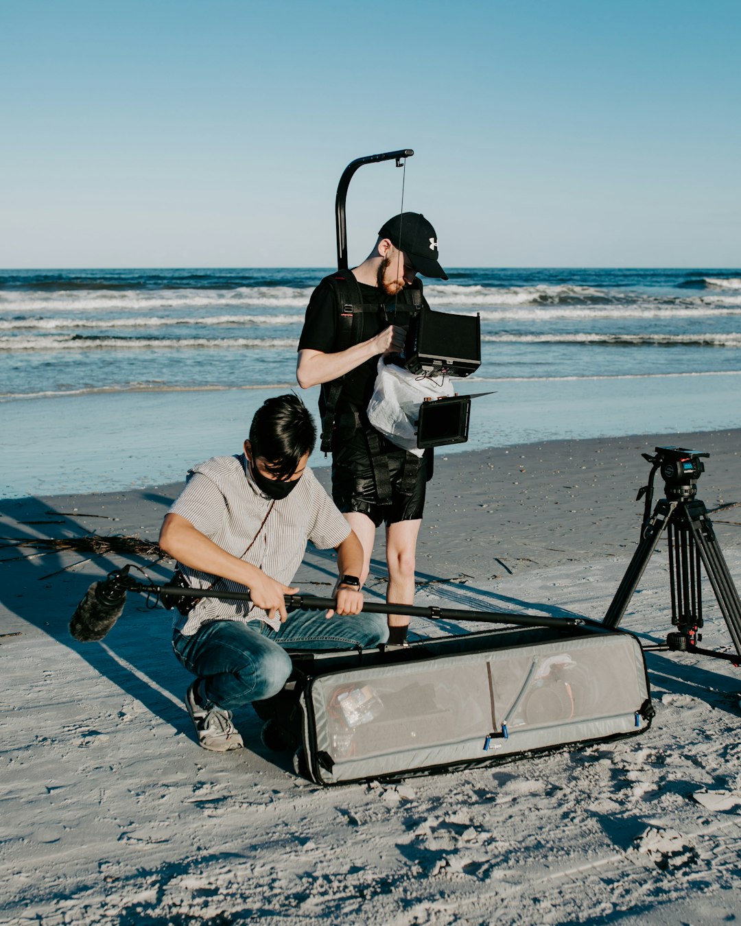 a man is filming another man on the beach film crew advertising setup video shooting