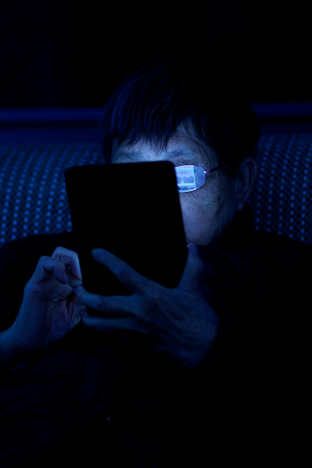 a man sitting in a dark room using a tablet computer data stream visualization glowing binary code person using smartphone at night