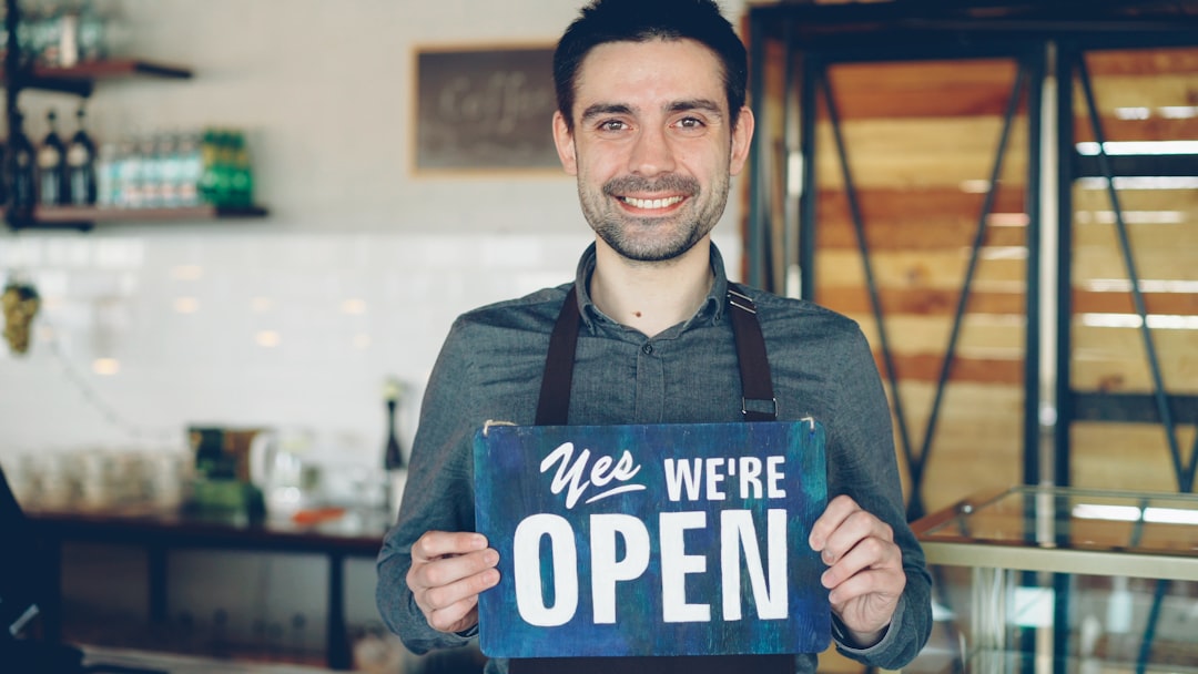 barista holds an open sign welcoming customers small business office customer service website integration