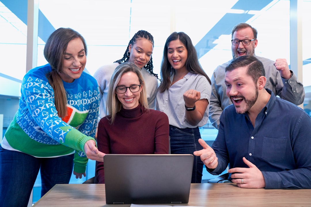 men and women sitting and standing while staring at laptop diverse team happy employees workplace spotlight