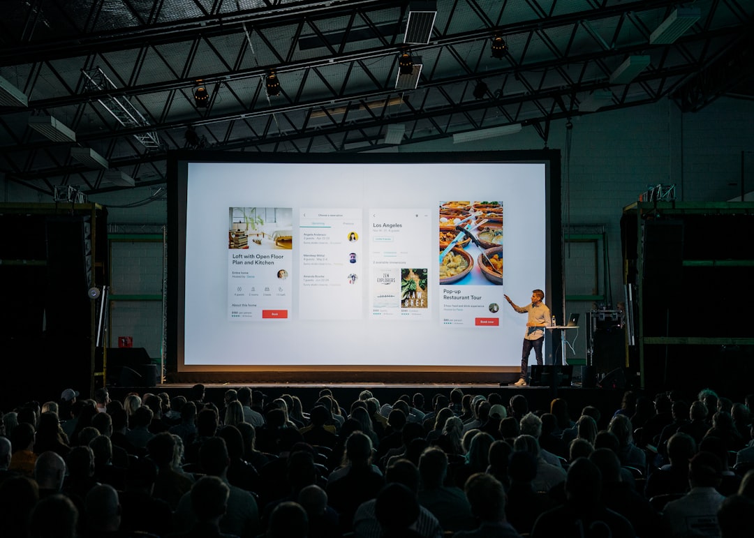 person discussing while standing in front of a large screen in front of people inside dim lighted room presentation mockup client pitch advertising concept