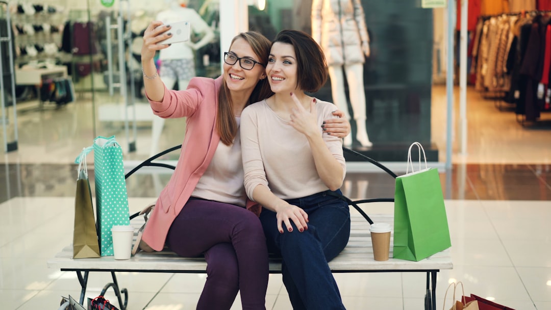 two smiling women taking a selfie in a shopping mall kohls cash usage checkout beauty purchase