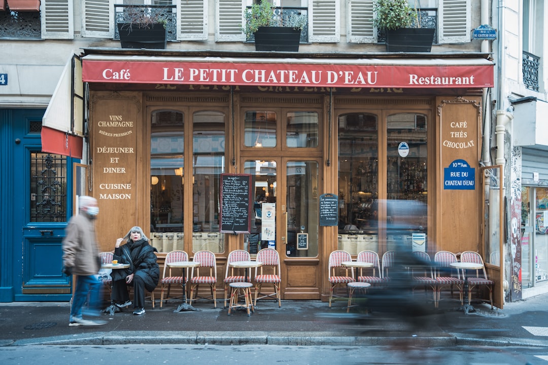 a couple of people sitting at a table outside of a restaurant paris travel charging devices coffee laptop