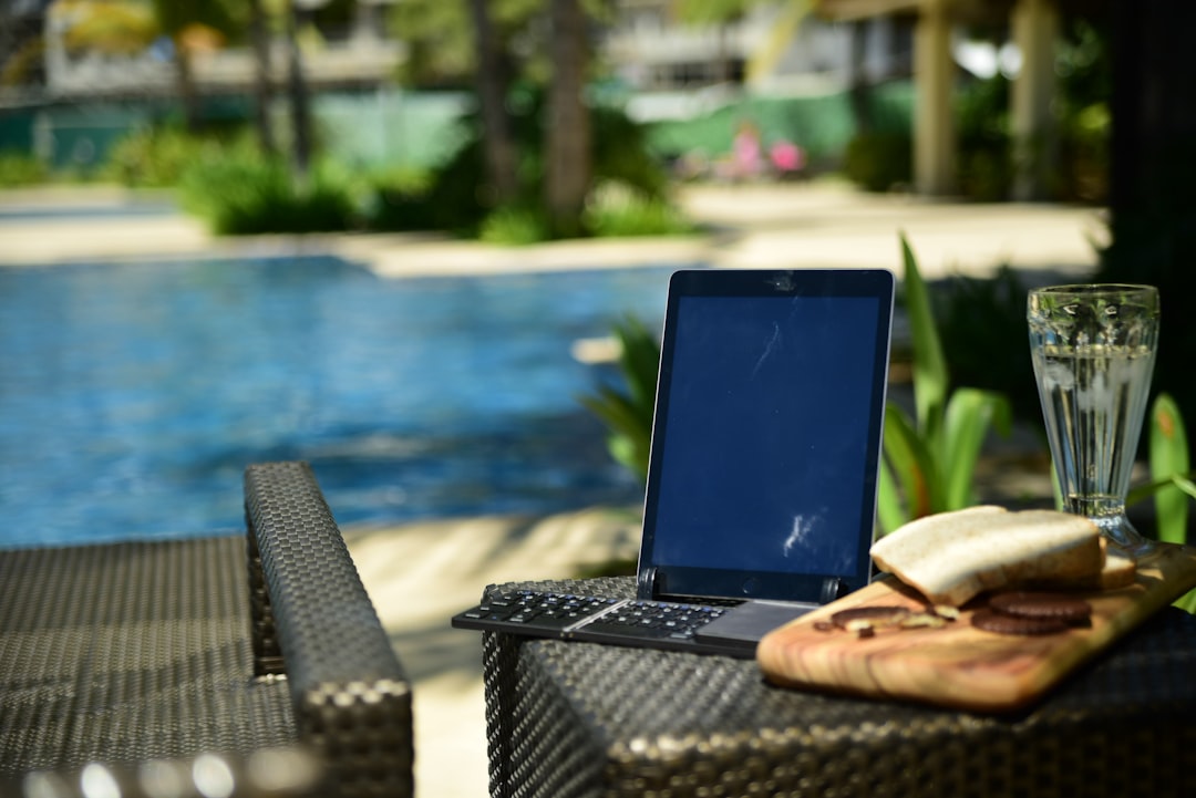 a laptop computer sitting on top of a table next to a pool wordpress plugin dashboard vacation rental booking calendar integration