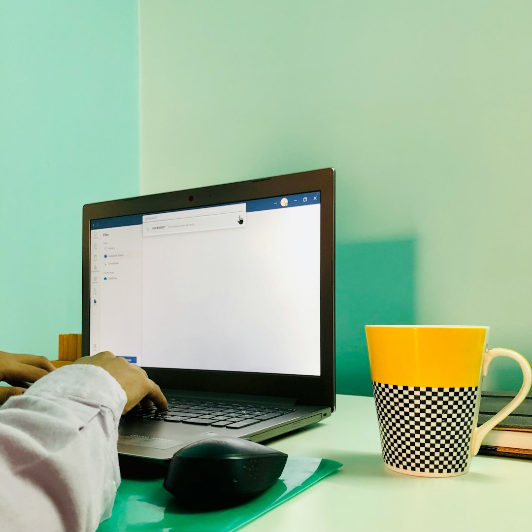 a person using a laptop computer on a desk email profiles microsoft outlook dual email management