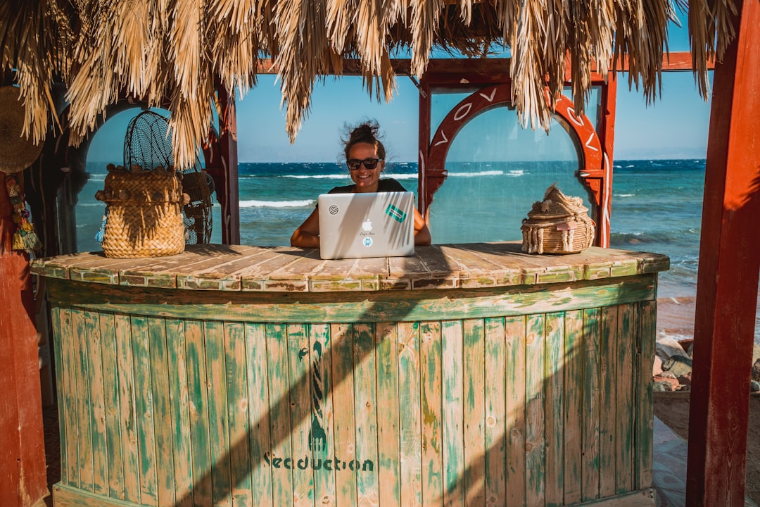 woman sitting on tiki bar facing silver laptop wordpress plugin dashboard vacation rental booking calendar integration
