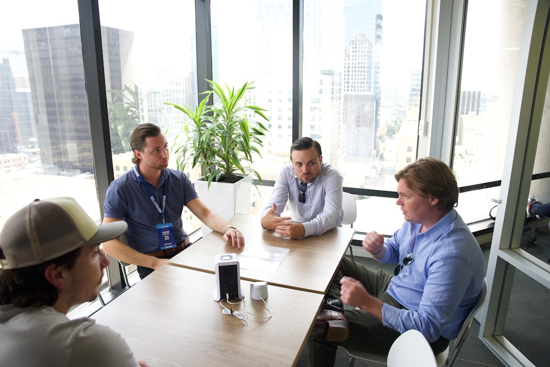 a group of men sitting around a table talking team meeting mentor apprentice modern workspace