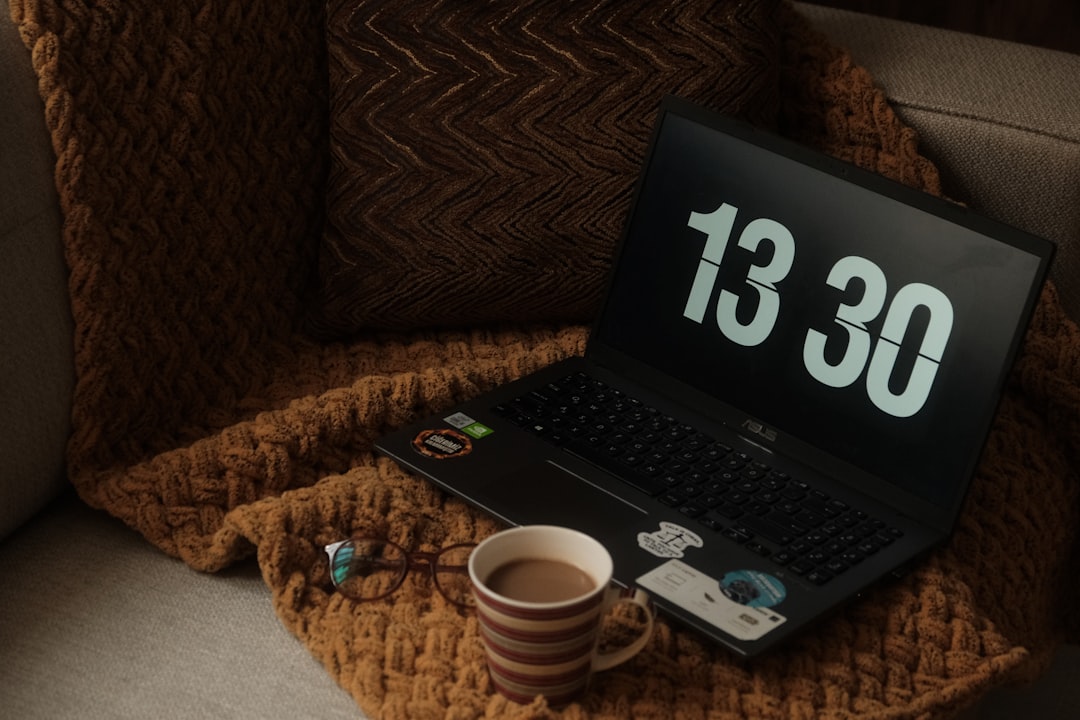 a laptop computer sitting on top of a couch next to a cup of coffee time tracking dashboard on laptop productivity timer running agency desk setup