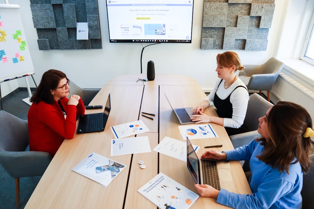 a group of women sitting around a table working on laptops sales team collaboration digital marketing meeting analytics presentation