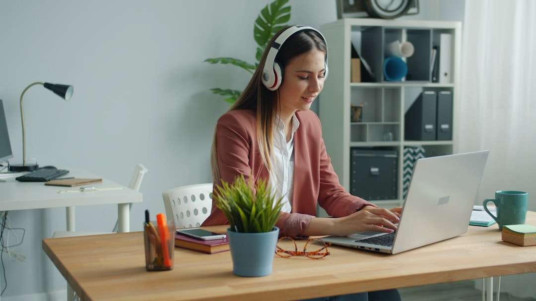 young woman wearing headphones works on laptop at desk customer support agent headset computer multilingual chat